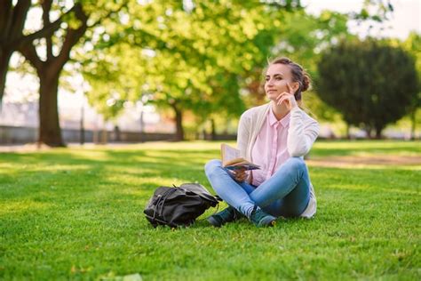 Premium Photo Beautiful Woman Sitting On Grass And Reading Book At