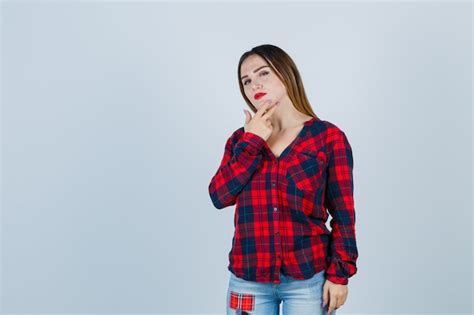 Retrato de señorita manteniendo los dedos en la barbilla en camisa a