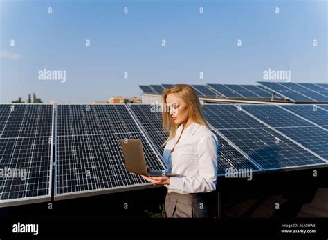 Investor And Solar Panels Blonde Woman With Laptop Near Blue Solar Panels Row On The Ground