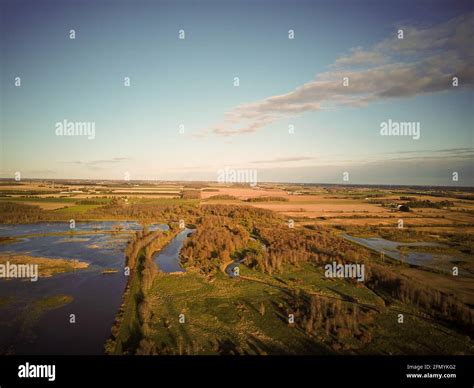 Aerial View Of Small River Flowing Through Green Marshy Riparian