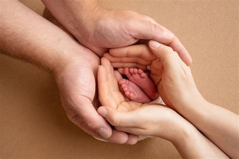 As palmas dos pais um pai e uma mãe seguram os pés de um filho recém