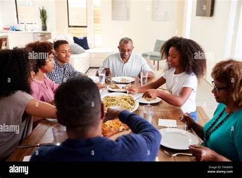 Three generation black family sitting at dinner table eating together ...