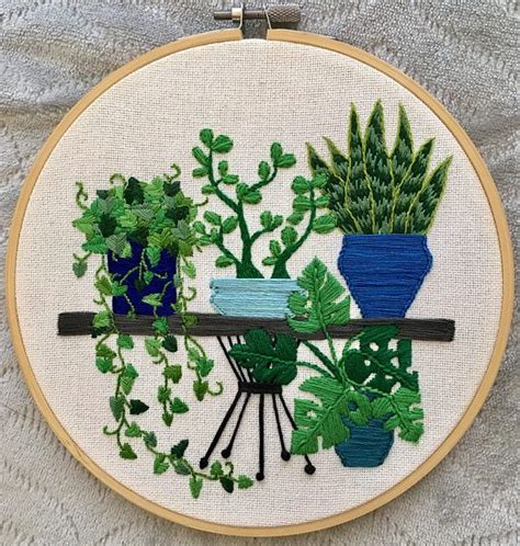 An Embroidery Project With Potted Plants On A White Surface Including