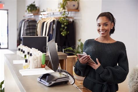 Female Assistant Smiling From The Counter In Clothing Store Stock Image