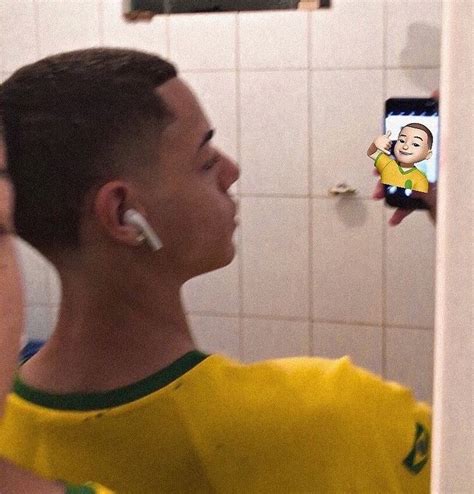 A Man With Ear Buds On His Ears Is Looking At Himself In The Bathroom