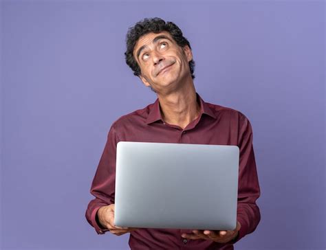 Free Photo Senior Man In Purple Shirt Holding Laptop Looking Up With