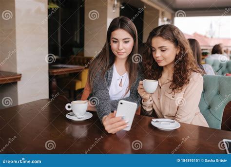 Two Girls Friend Drink Coffee In Cafe And Look In Smat Phone Happy