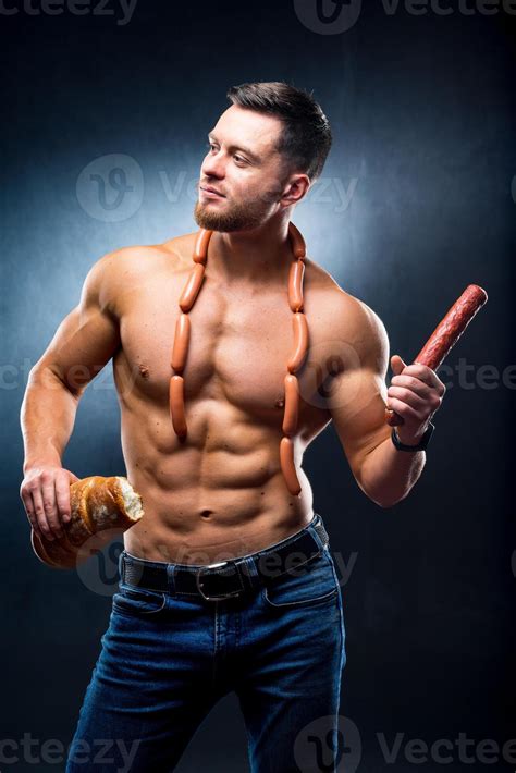 Bodybuilder With Naked Torso Smoked Sausage In One Hand Sausages On A