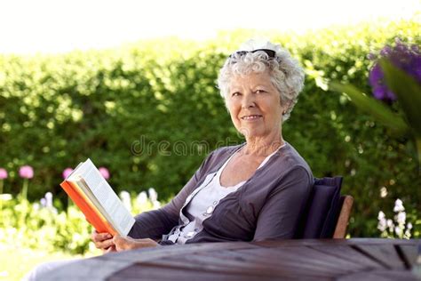 Livro De Leitura Superior Feliz Da Mulher No Jardim Foto De Stock