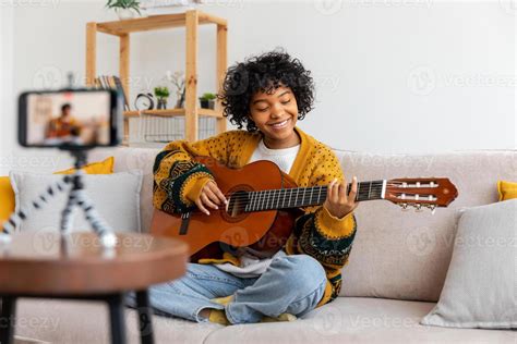 Blogger guitarist. Happy african american girl blogger playing guitar ...