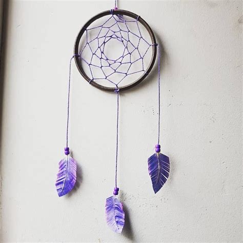 A Purple Dream Catcher Hanging From The Side Of A Wall