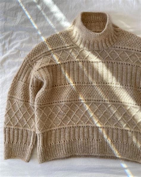 A Sweater Is Laying On A Bed With The Sun Shining Through It S Shadow