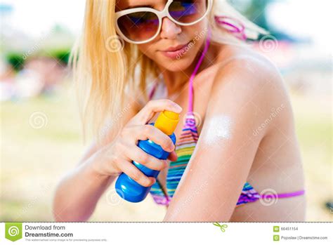 Femme Blonde Dans Le Bikini Et Des Lunettes De Soleil Mettant Sur La Protection Solaire Photo