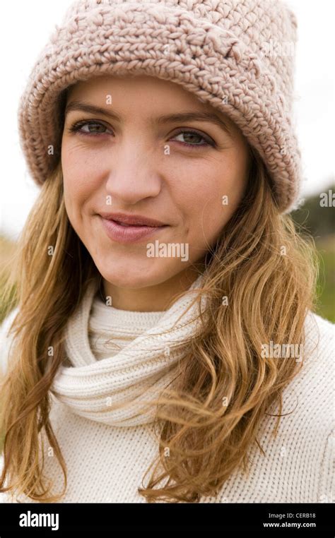 Female With Long Blonde Hair Wearing Cream Jumper And Biege Woolly Hat Looking To Camera Smiling