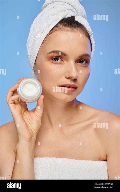 Attractive Woman With Towel On Head Showing Jar Of Face Cream On Blue