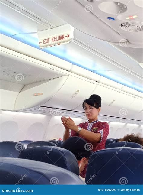 A Female Flight Attendants On The Aisle Show Passengers About Safety