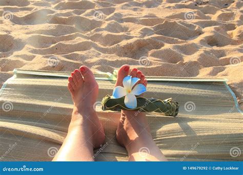 Female Feet On The Sand Sith A Hawaiian Flower Band Stock Photo