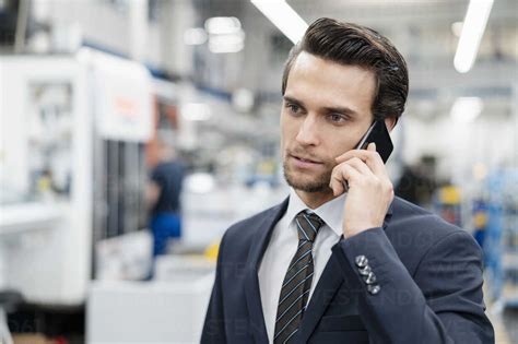 Portrait Of Businessman On Cell Phone In A Factory Stock Photo