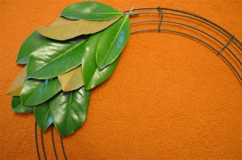 A Close Up Of A Wreath Made Out Of Metal Wire And Green Leaves On An