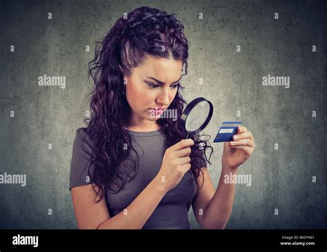 Curious Woman Looking At Credit Card Through Magnifying Glass Isolated