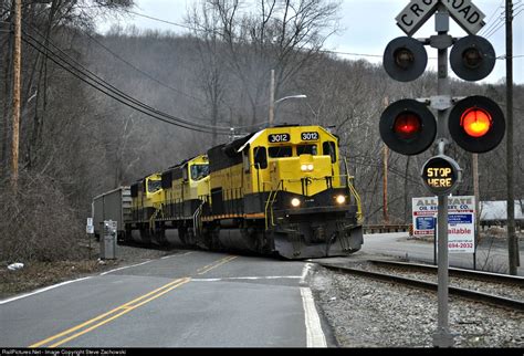 a yellow and black train traveling down tracks next to a red light at ...