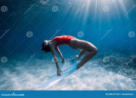 Woman Freediver In Red Swimsuit With White Fins Posing Underwater In