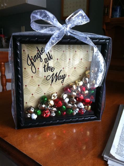 A Christmas Decoration With Bells In A Frame On A Wooden Table Next To