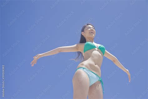 青空の下で両手を広げる水着女性 Foto De Stock Adobe Stock