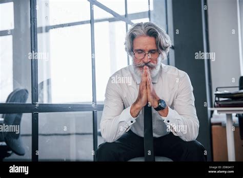 Portrait Of Mature Businessman With Grey Hair And Beard In Formal Clothes That Sitting In The