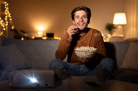 Excited Man Watching Movie Using Projector Eating Popcorn At Home Stock