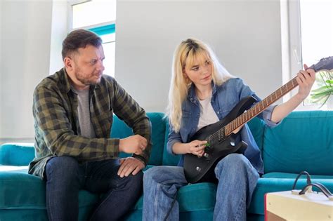 Padre enseñando a su hija adolescente a tocar la guitarra eléctrica