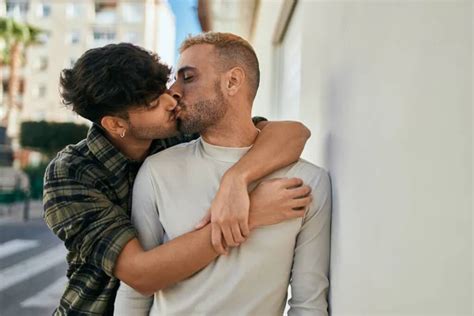 Joven pareja gay abrazándose y besándose en la ciudad 2024