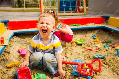 Premium Photo | Grubby kids playing in the sandbox. boy crying and ...