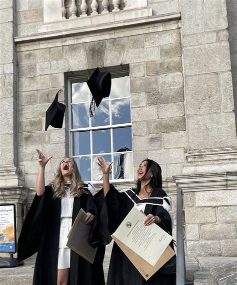 Two Women In Graduation Gowns Throwing Their Caps Into The Air While