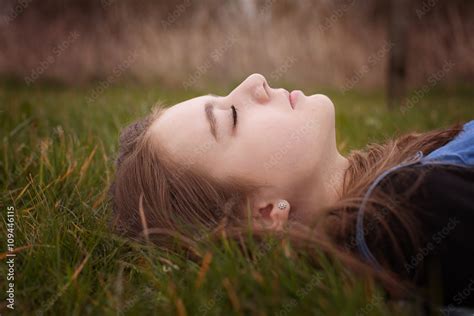 Pretty Teenage Girl Lying Down On Grass With Her Eyes Closed Stock