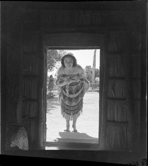 A Māori Woman Dressed In Costume Looking Into A Whare Whakarewarewa