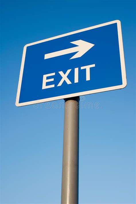 Exit this way. Exit sign silhouetted against a clear blue sky # ...