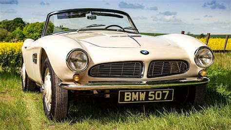 an old bmw sports car is parked in the grass