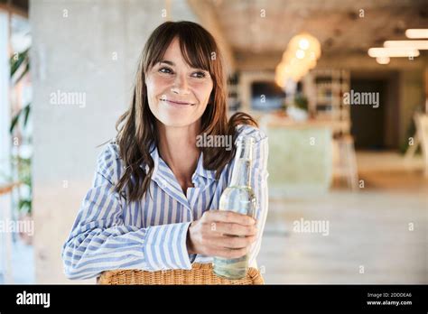 Smiling Mature Woman Looking Away While Holding Beer Bottle Sitting At Home Stock Photo Alamy