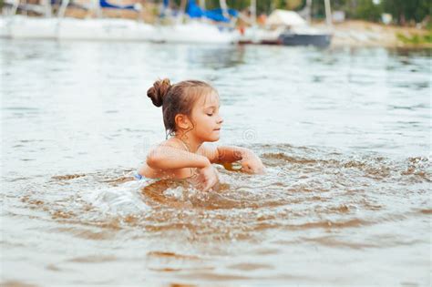 Little Happy Girl Plays With Water And Splashes Of Water In The Sea