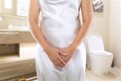 Las mujeres en un vestido blanco quieren orinar en el baño Orinar o