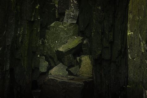 A dark cave with rocks and moss · Free Stock Photo