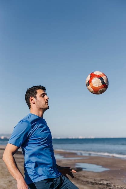 Kerl Der Fu Ball Am Strand Spielt Kostenlose Foto