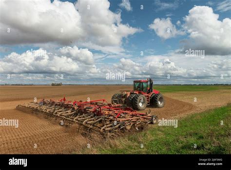 Red tractor cultivates the farm field. Spring agricultural works in ...