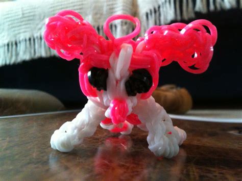 A Small Toy Dog With Pink And White Beads On Its Head Sitting On A Table