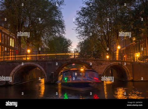 Netherlands Dusk On The Amsterdam Canal Pleasure Boat Under The Stone