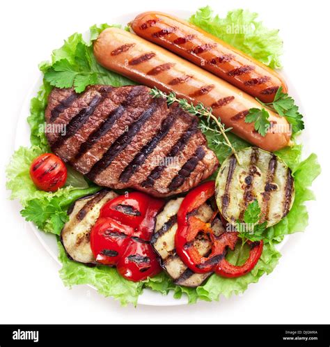 Grilled Steak Sausages And Vegetables Over Lettuce Leaves Stock Photo