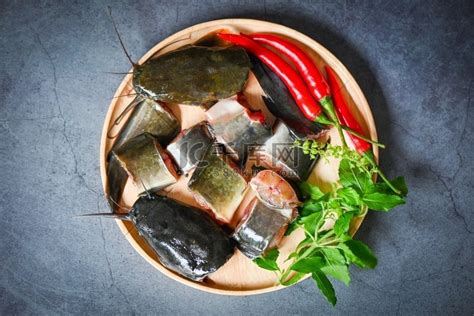 木盘上的鲶鱼片、新鲜的生鲶鱼菜单淡水鱼、用于烹饪食物的鲶鱼、用配料香草和香料切碎的鱼 — 顶视图高清摄影大图 千库网