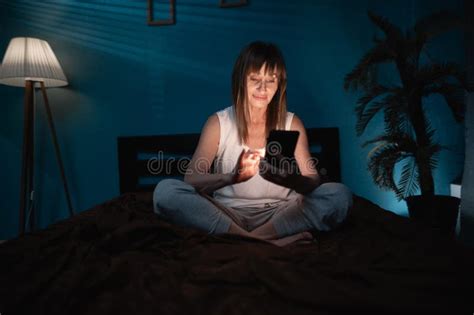 Mature Woman Uses Smartphone In Bed At Night Lady In T Shirt Browsing