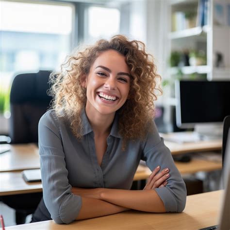 Una Mujer Sonriente Se Sienta En Un Escritorio Con Un Monitor De